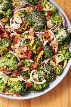 a bowl filled with broccoli, onions and bacon on top of a wooden table