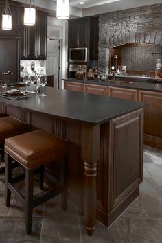 a large kitchen with dark wood cabinets and marble flooring, along with two bar stools