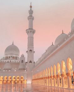 a large white building with many arches and domes on it's sides at dusk