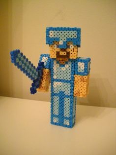 a lego man holding a blue object on top of a white table in front of a wall