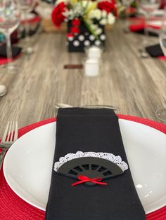 the table is set with black napkins and red place mats, along with silverware