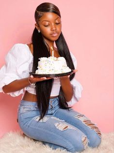 a woman sitting on the floor holding a plate with a cake in front of her