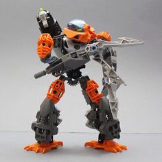 an orange and black robot is standing in front of a gray background