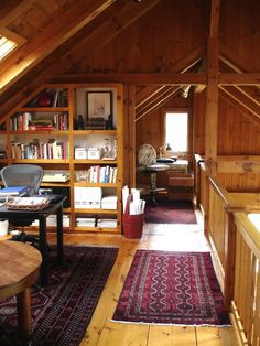 an attic with wood paneling and lots of bookshelves on the walls, along with a rug