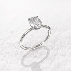 a white gold ring with a pear shaped diamond in the center on a snow covered surface