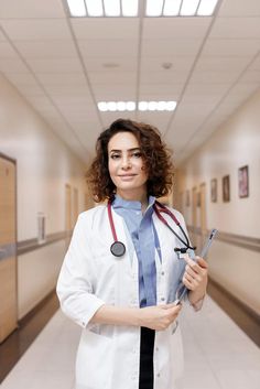 a woman in a white lab coat and stethoscope standing in a hallway