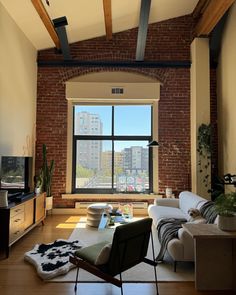 a living room filled with furniture and a large window overlooking a cityscape in the distance