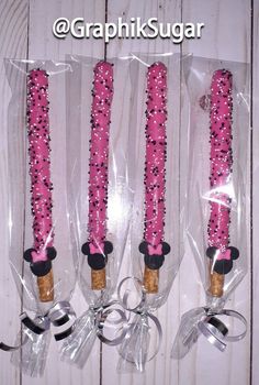 three pink candles are wrapped in plastic and tied with black ribbon on white wood planks