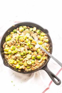 a skillet filled with brussel sprouts and mushrooms on top of a table