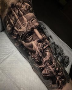 a man's leg with a black and grey tattoo on it, depicting the face of jesus