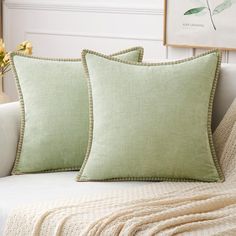 two green pillows sitting on top of a white couch