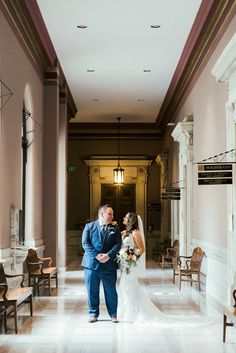 a bride and groom standing in the middle of a hallway at their wedding reception venue