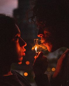 a man and woman are looking at each other while holding a lit match in their hands