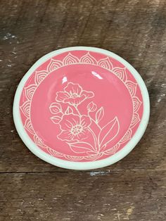 a pink and white plate sitting on top of a wooden table