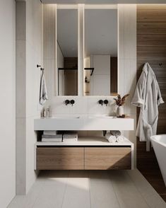 a modern bathroom with two sinks and a bathtub in the corner, along with towels hanging on the wall