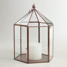 a glass candle holder with a single white candle in it's center, on a white background