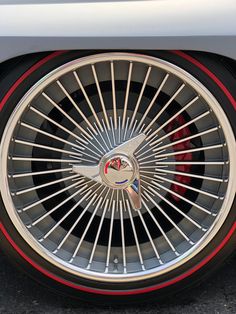 the front wheel of a car with chrome spokes and red stripeing on it