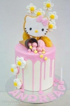 a hello kitty cake with pink icing and yellow flowers on top, sitting on a table