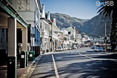 an empty street with buildings and mountains in the background