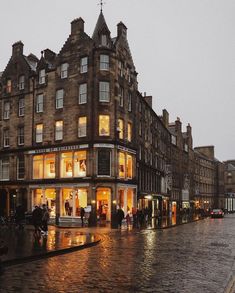 people are walking down the street in front of buildings on a rainy day with rain