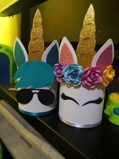 two cups with unicorn faces and flowers on them sitting on a shelf next to other items