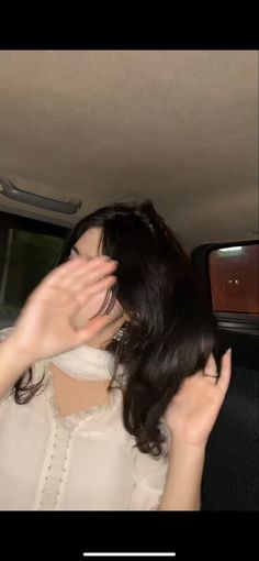 a woman in the back seat of a car holding her hand up to her face