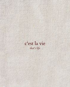 the words cest la vie are written in red ink on a white linen background