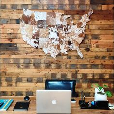 a laptop computer sitting on top of a wooden desk in front of a wall map