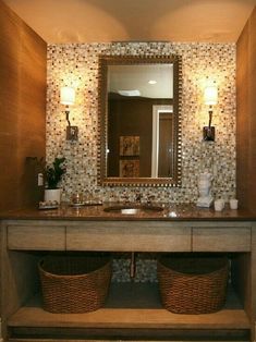 a bathroom vanity with two baskets under the sink and a mirror above it that has lights on