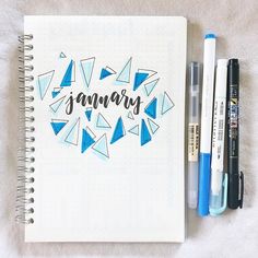 a notebook with the word january written on it next to two markers and a pen