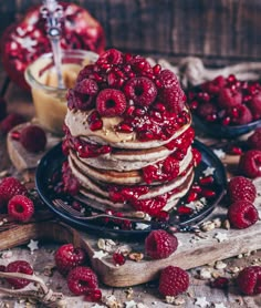 a stack of pancakes covered in raspberries and powdered sugar