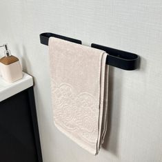 a white towel hanging on the wall next to a black shelf