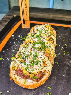 an open faced sandwich with meat, cheese and herbs on it sitting on a tray