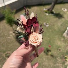 a person holding a flower in their left hand with grass and flowers on the other side