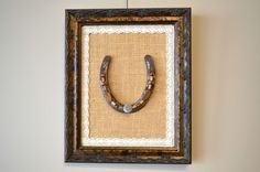 a frame hanging on the wall with a cow horn in it