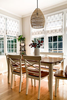 a dining room table with four chairs and a basket hanging from it's ceiling