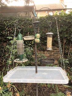 a bird feeder hanging from a pole in a garden with birds on it's sides