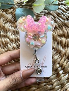 a hand holding a key chain with a pink mickey mouse head on it's side