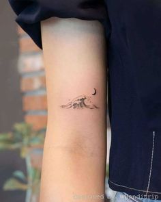 a person with a small tattoo on their arm that has a wave coming out of it