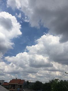 the sky is full of clouds and some houses are in the foreground with trees on either side