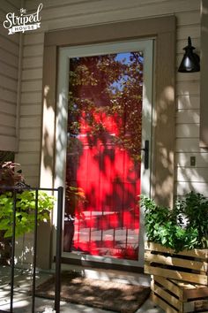 a red screen door on a house with potted plants in the front and side