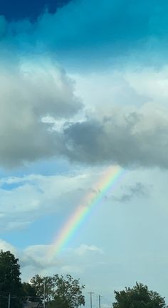 a rainbow is seen in the sky above some trees