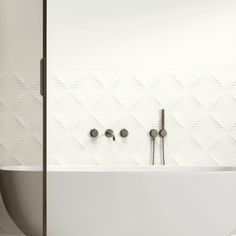 a white bath tub sitting next to a wall mounted faucet