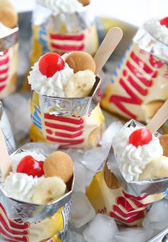 small ice cream sundaes with banana slices and cherries on top, in tin foil cups