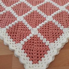 a pink and white crocheted rug on top of a wooden floor