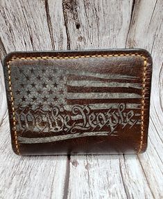 Custom made high quality hand crafted leather wallet. Perfect minimalist bifold wallet. Includes two card pockets and two stash pockets. Measures at 4"×3".  Beautiful understated "We the People" with the American flag laser engraving, wonderful patriotic gift. Enjoy a stylish and functional way to carry the essentials. Makes a wonderful gift that can be treasured for generations.  Made from the highest quality Horween leather from one of the oldest American tanneries, handcrafted to a luxurious finish.  This leather is designed to wear beautifully over time. Handmade and handstitched with the utmost care right here in the United States of America. We hope you love this genuine leather item for a lifetime. Custom Leather Wallets With Card Slots, Custom Handmade Trifold Wallet, Custom Handmade Rectangular Trifold Wallet, Custom Hand Tooled Brown Wallet, Custom Brown Hand Tooled Wallets, Custom Hand-tooled Rectangular Trifold Wallet, Custom Hand-tooled Trifold Wallet, Custom Handmade Brown Trifold Wallet, Leather Wallets With Engraved Logo For Everyday Use