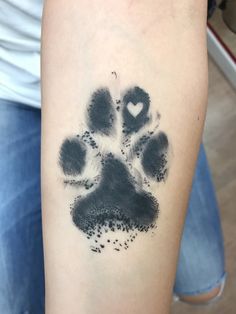 a person with a tattoo on their arm that has a dog paw print in the shape of a heart