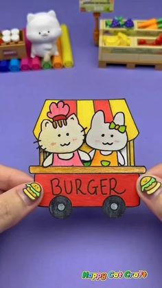 a person holding up a paper cut out of a burger truck