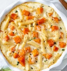 a white dish filled with pasta and carrots