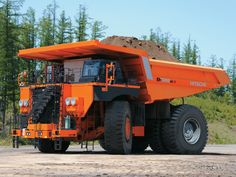 an orange dump truck is parked in the dirt